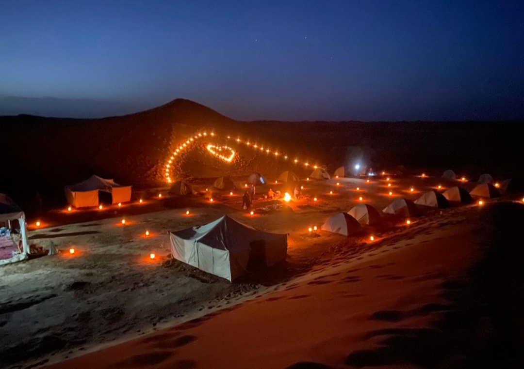 Bivouac nomade illuminé d'un cœur de lanternes sous les étoiles