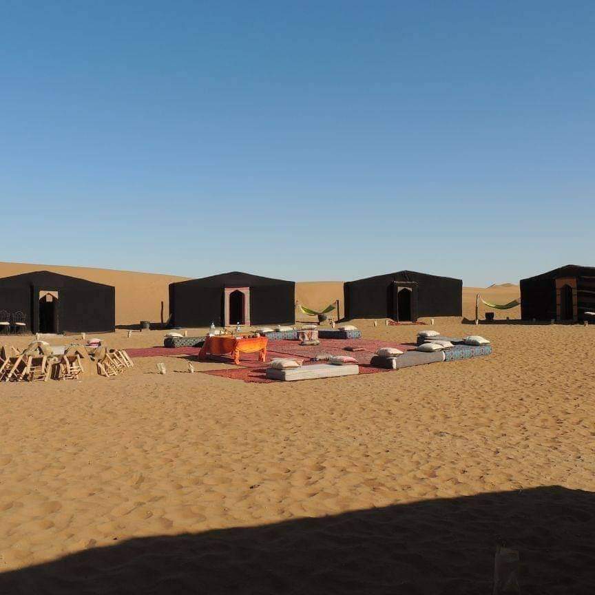 Campement traditionnel en tentes de laine noire et salon berbère dans les dunes